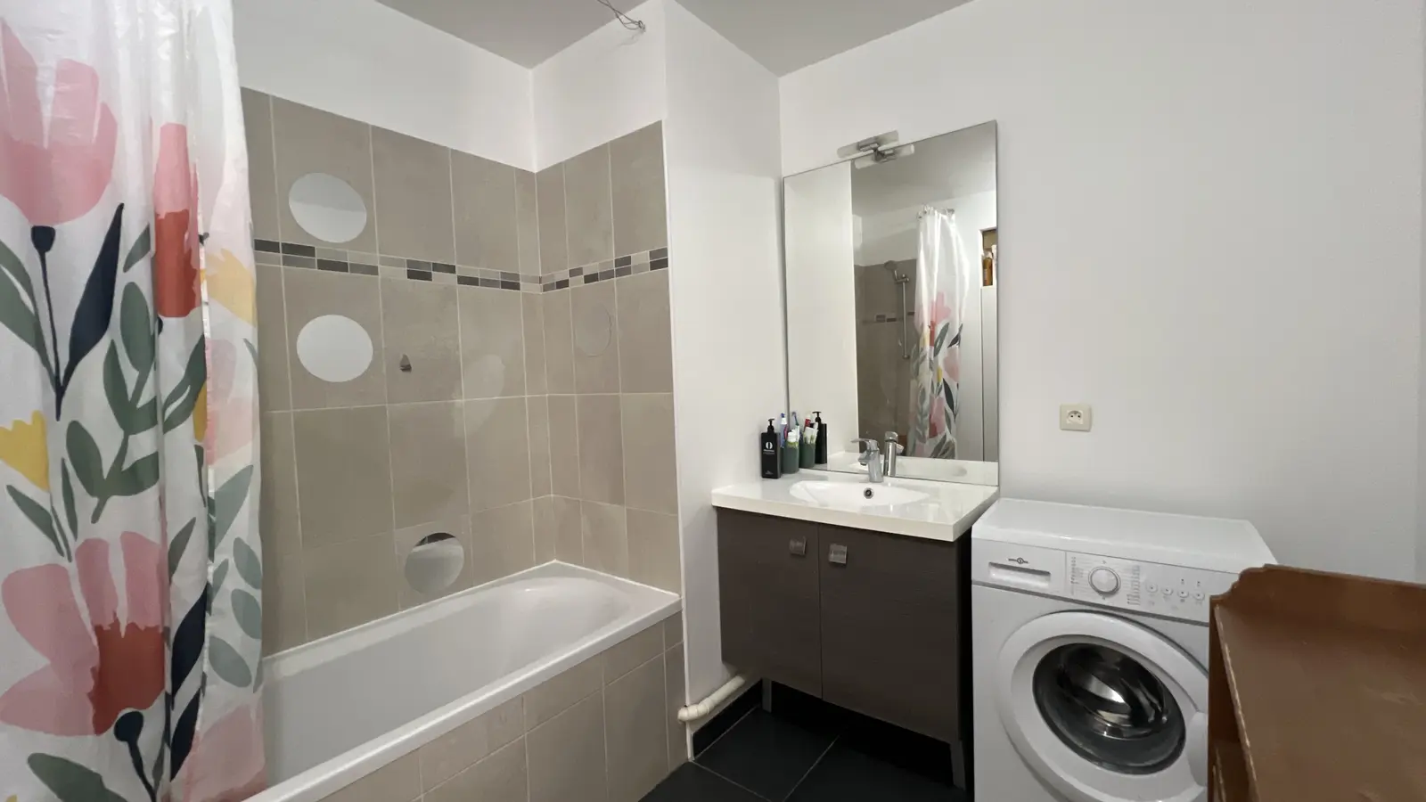 Salle de bains avec baignoire, vasque et espace lave-linge