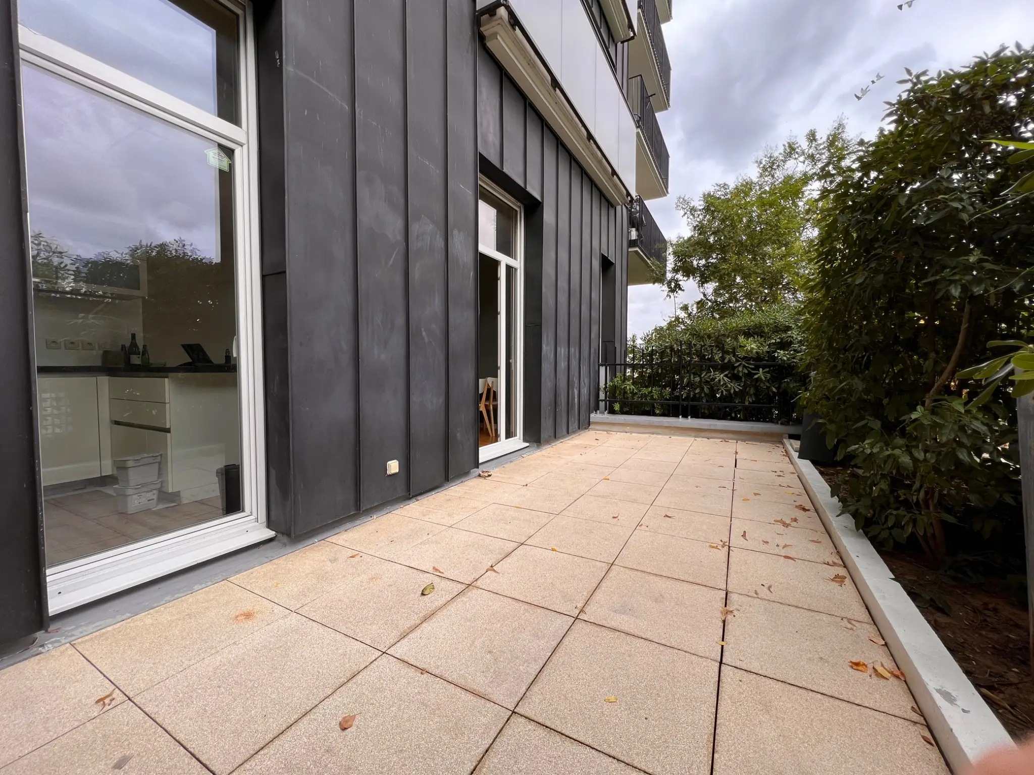 Terrasse privative du rez-de-jardin, bordée de végétation