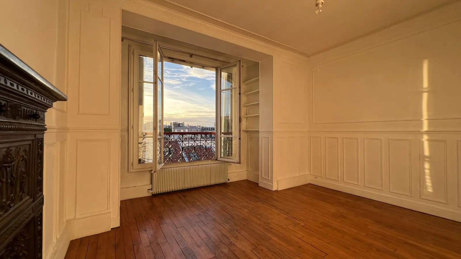 Lumière du soir dans le salon et vue sur les toits parisiens