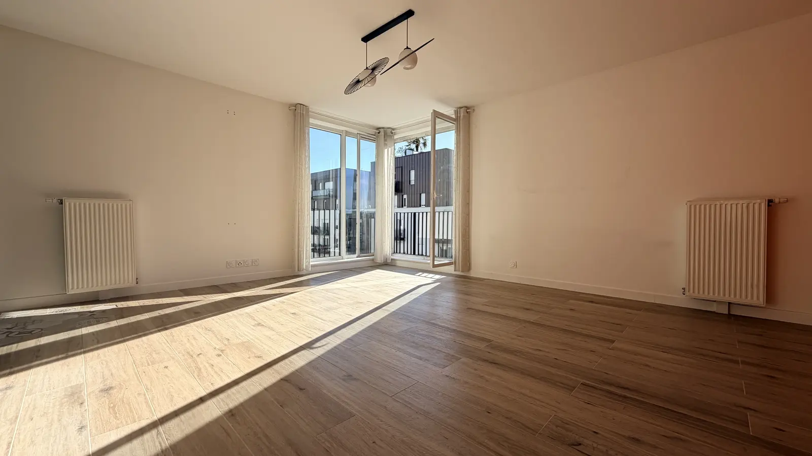 Séjour vide et lumineux avec parquet, double ouverture et accès au balcon
