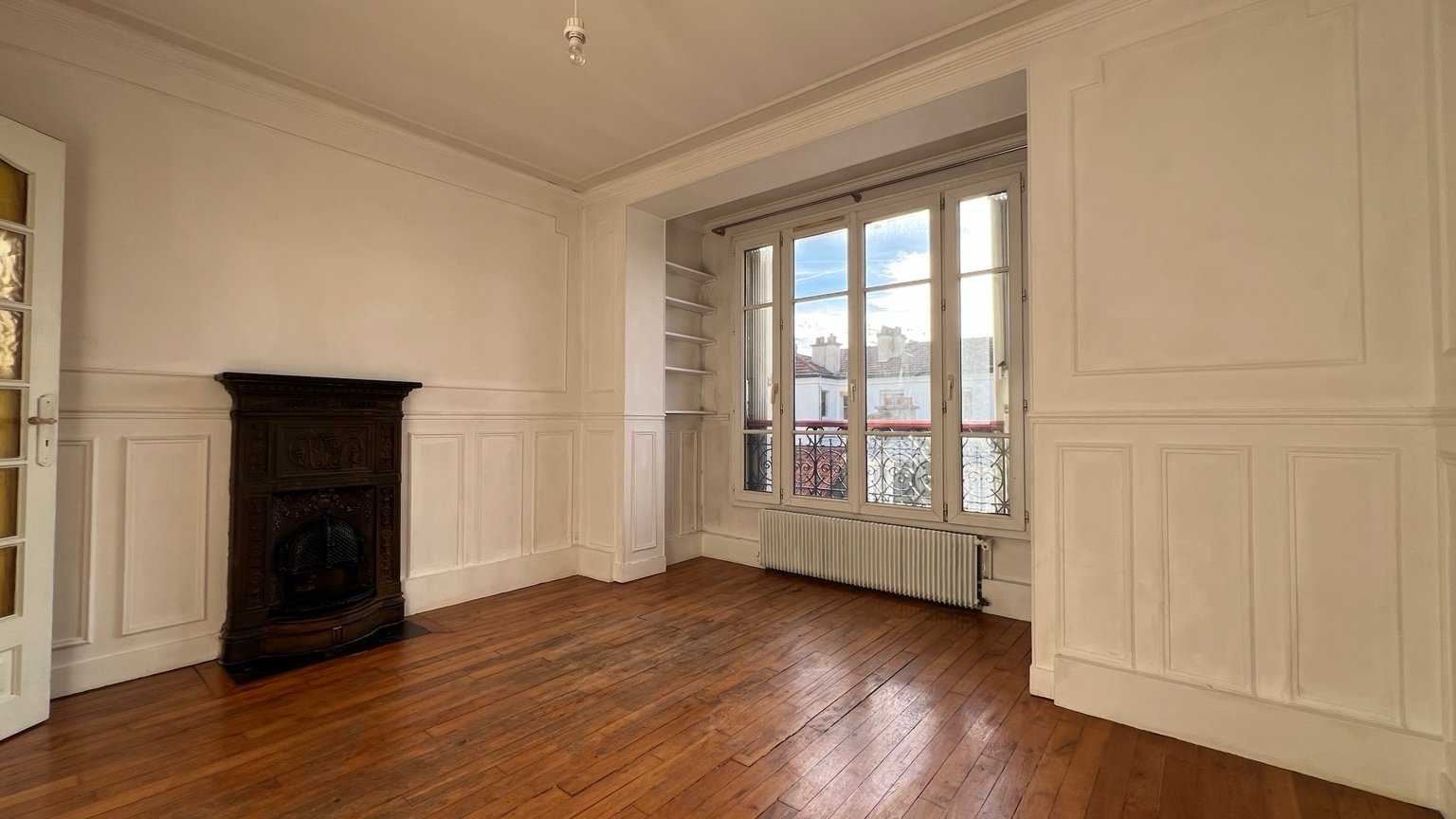 Pièce d'angle avec parquet, moulures, poêle ancien et deux fenêtres