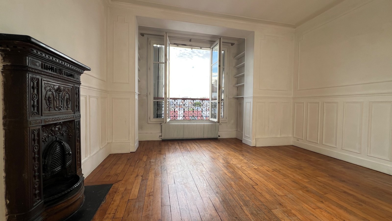 Salon vide avec parquet et poêle prussien