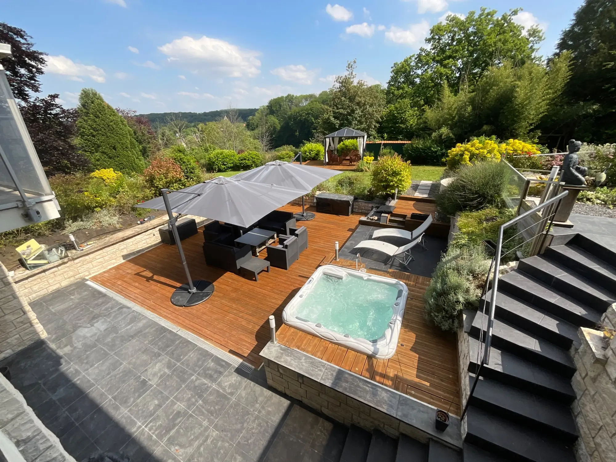 Terrasse en bois avec jacuzzi et vue sur le jardin